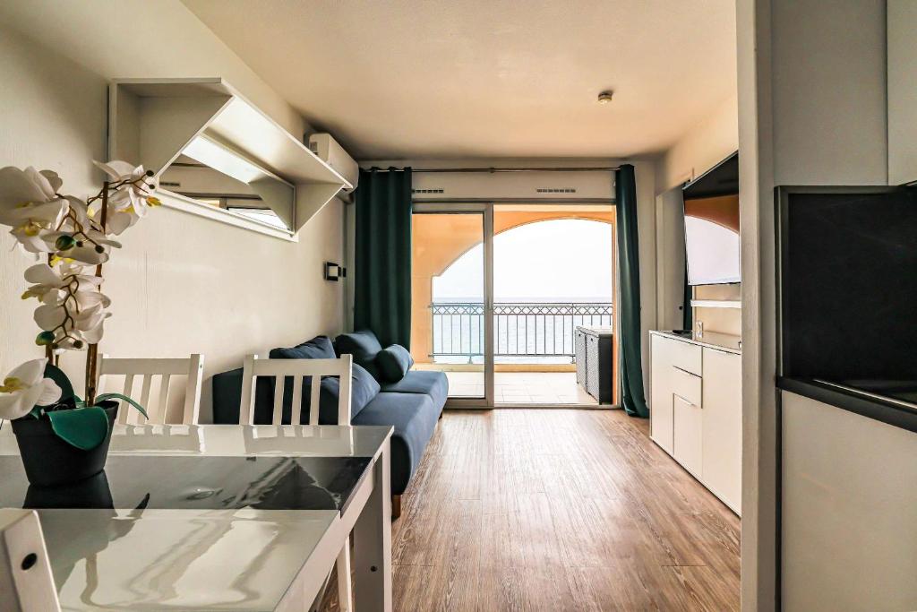 un salon avec un canapé bleu et une cuisine dans l'établissement Le Cannes Beach 799 - terrasse vue mer panoramique, à Cannes
