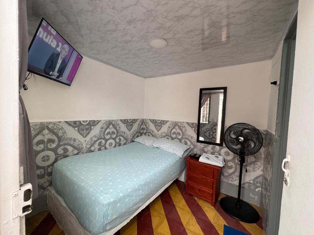 a bedroom with a bed and a tv on the wall at Hotel Familiar in Medellín