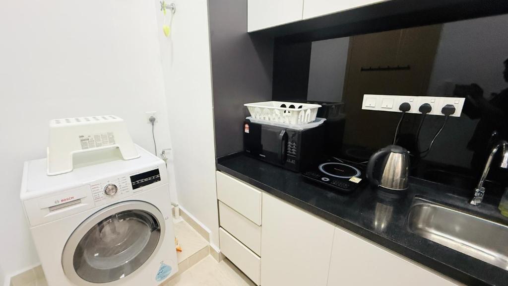 a kitchen with a washing machine and a sink at Colony Service Suites Kuala Lumpur in Kuala Lumpur