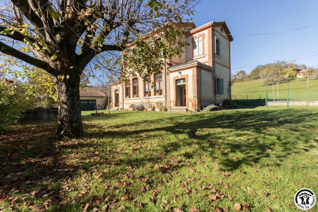 an old house with a tree in front of it at Ancienne ecole in Montbrun-Bocage