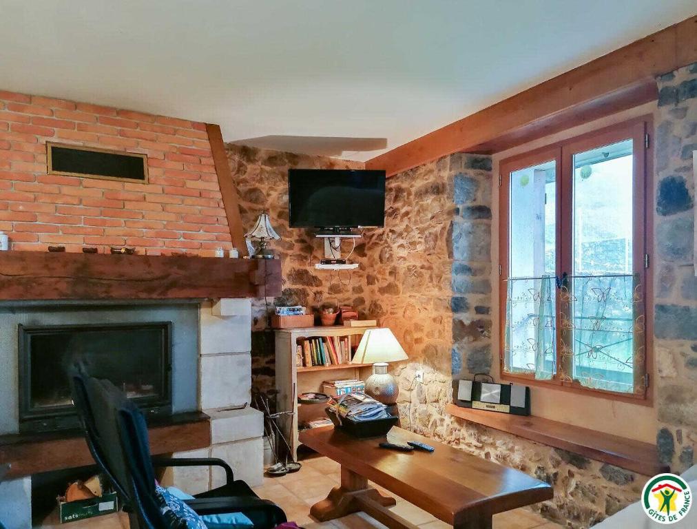 een woonkamer met een bakstenen muur en een open haard bij Chez courrier in Razecueillé