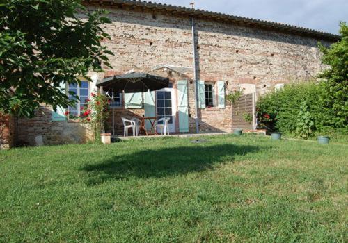 a brick house with an umbrella in a yard at Granny in Pibrac