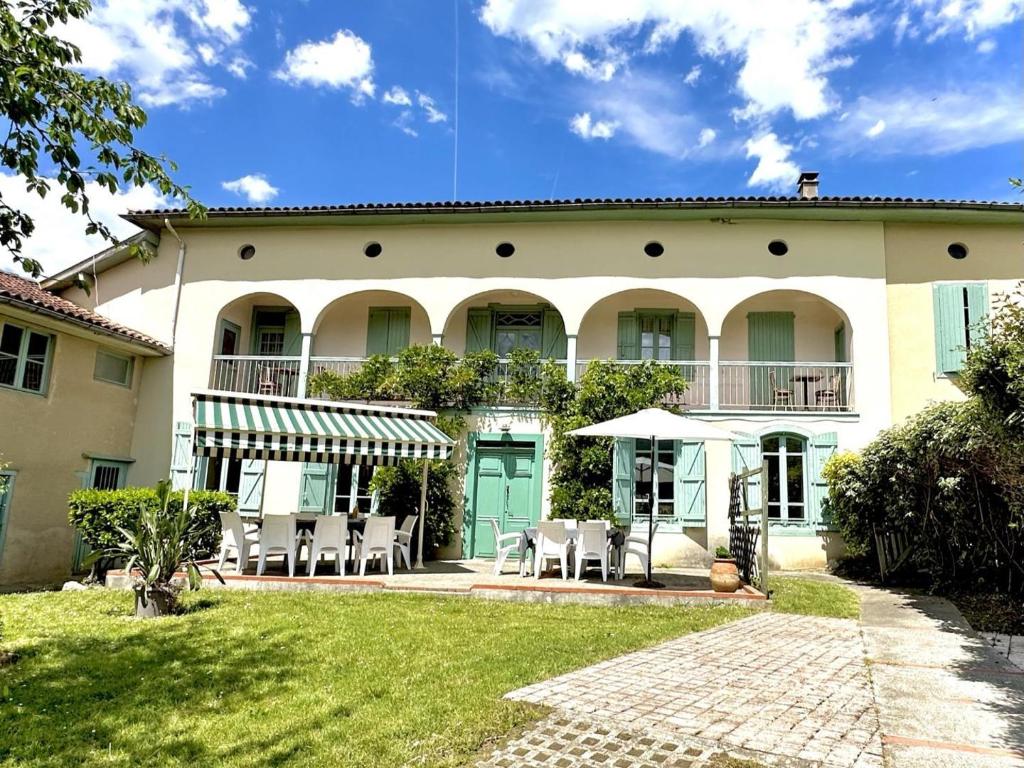 a large house with tables and chairs in front of it at Le clos saint-paul - comminges in Estadens