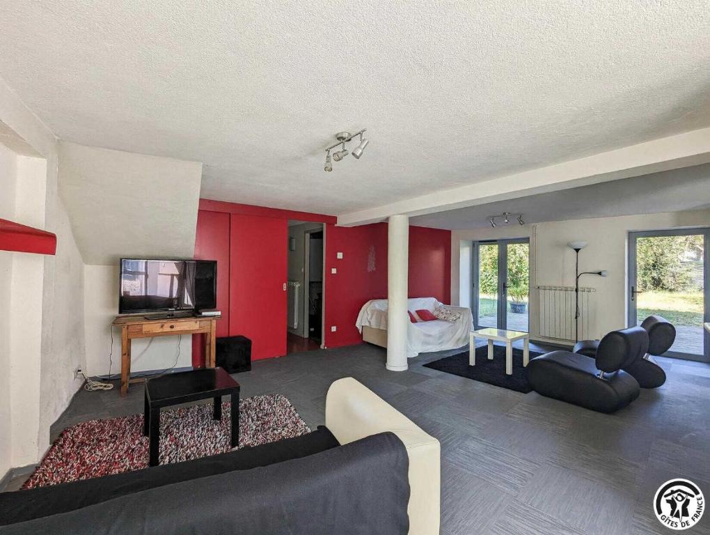 a living room with a couch and a tv and a bedroom at Le cagire in Labarthe-Rivière