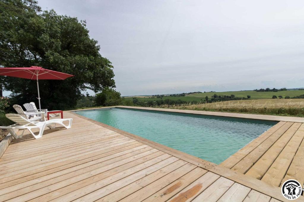 a swimming pool with a deck and an umbrella at Les pyrénées in Aurin