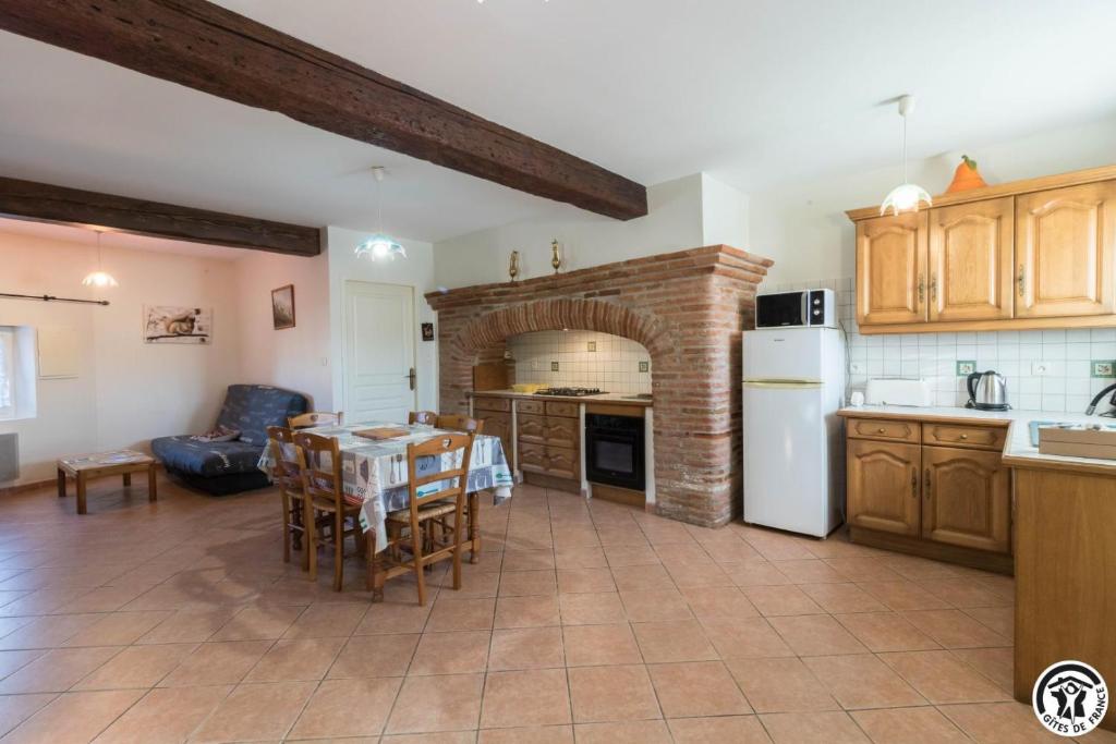 een keuken met een tafel en een keuken met een open haard bij Saint martin in Beaumont-sur-Lèze