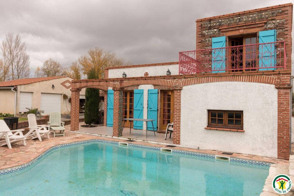 a villa with a swimming pool in front of a house at Au village in Roques Sur Garonne