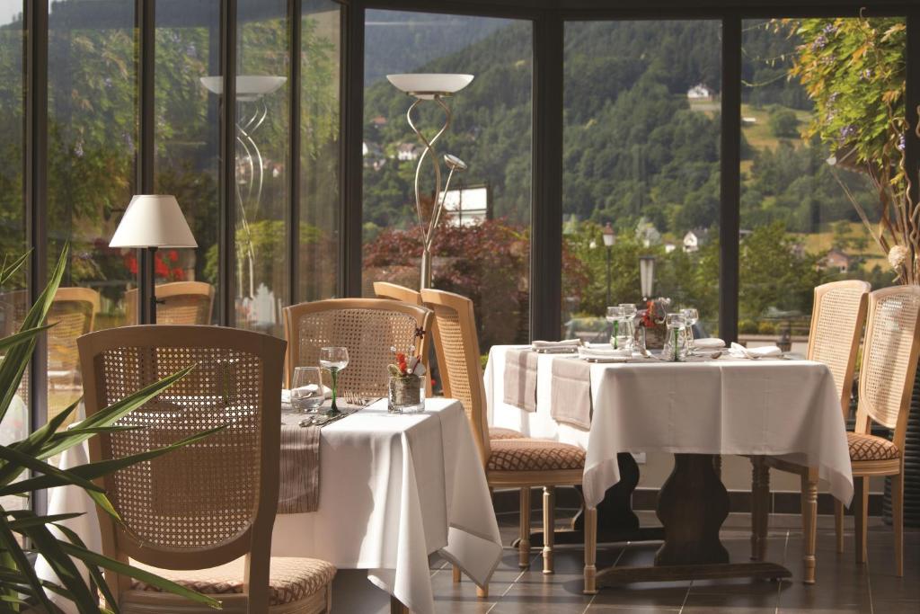 a restaurant with white tables and chairs with a view at Parc Hôtel in Wangenbourg