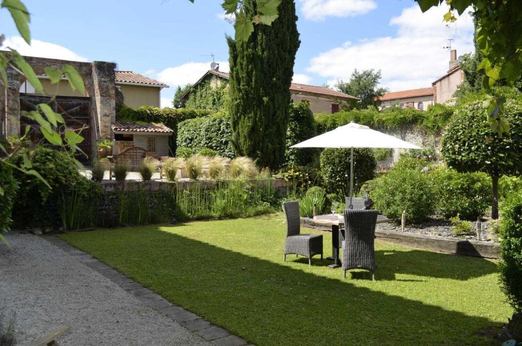 a garden with an umbrella and a table and chairs at Le sourire des anges in Saint-Élix-le-Château