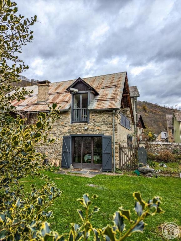 an old stone house with a metal roof at Le clos de bérande in Oô