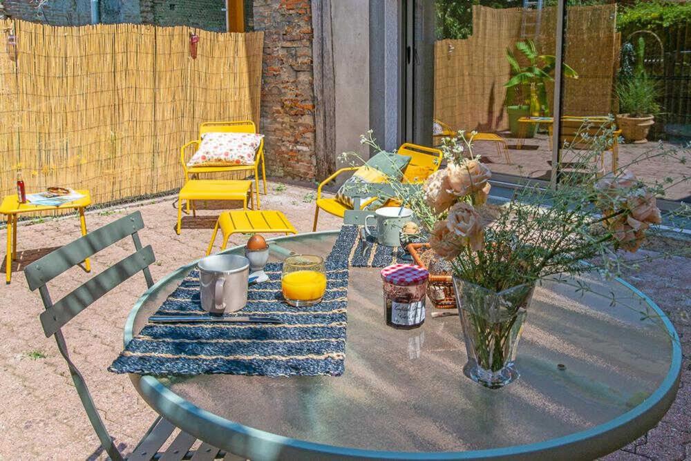 a glass table with a vase of flowers on it at La grange des rampeaux in Saint-Lys