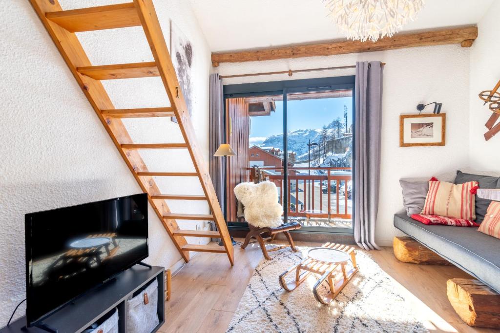 Il comprend un salon avec un escalier et une télévision. dans l'établissement Le chalet de Lili 2 pièces duplex, skis aux pieds, balcon, à Tignes