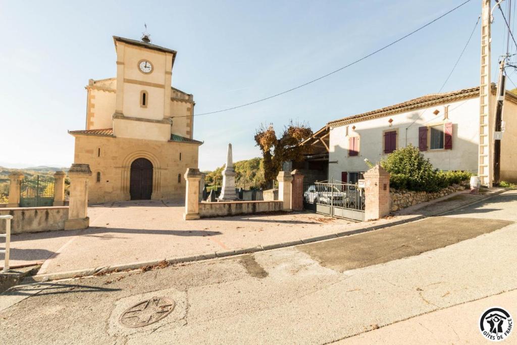a church with a clock tower next to a street at Gîte les ecureuils in Montclar-de-Comminges