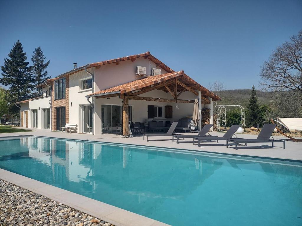 a villa with a swimming pool in front of a house at Villa la sauzière in Buzet-sur-Tarn