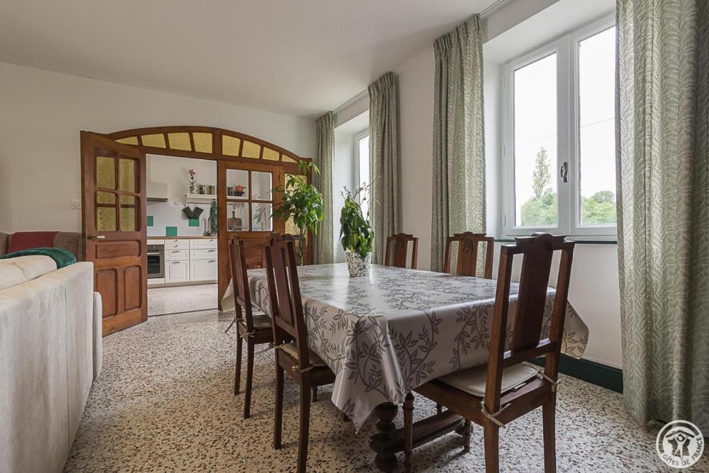 a dining room with a table and chairs and a kitchen at L'ecole à l'ancienne in Aulon