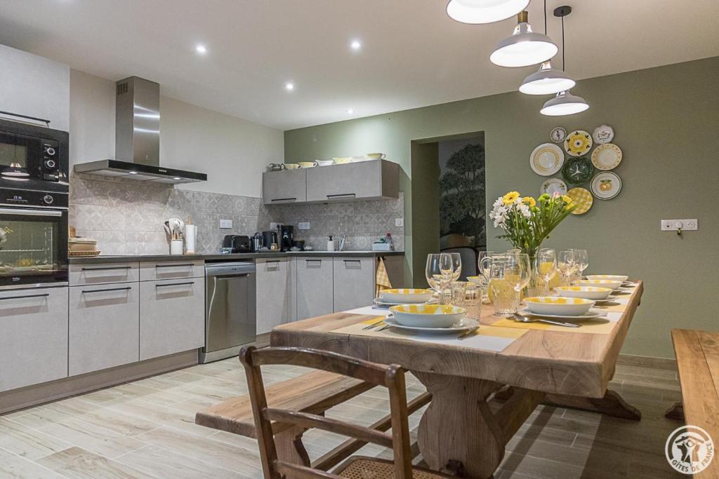 a kitchen with a wooden table with plates and wine glasses at Le logis du lièvre in Lodes