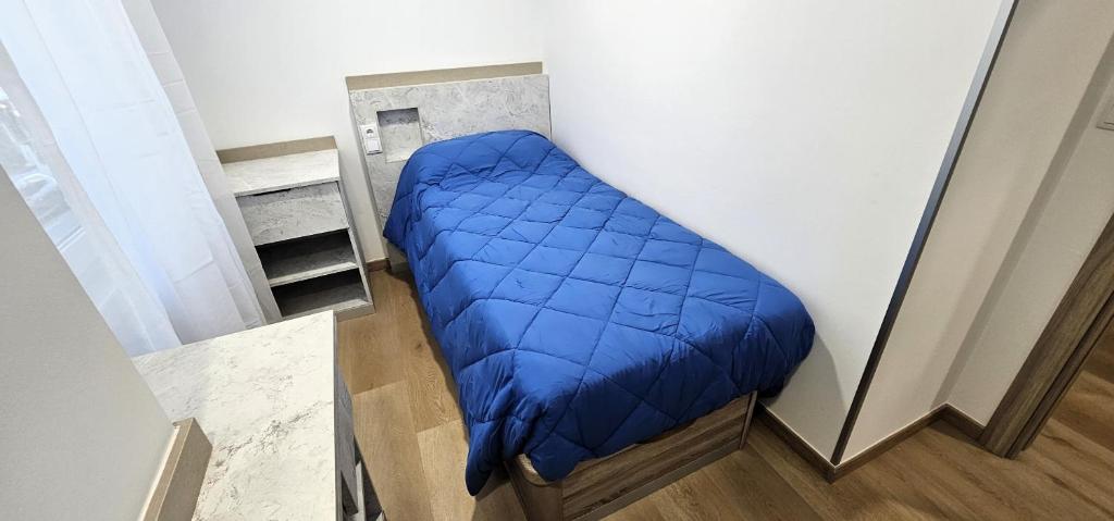 a blue bed in the corner of a room at Vacansis Habitaciones y Alojamientos A Coruña in Visma