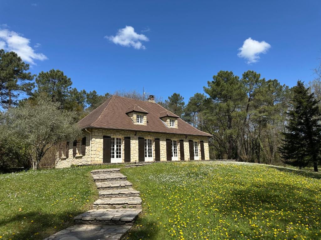 une maison sur une colline herbeuse avec un chemin dans l'établissement Le Peruguet - maison avec piscine et bois privé, à Margueron