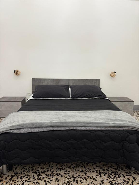 a bedroom with a large bed with a black comforter at MiMì House in Nardò