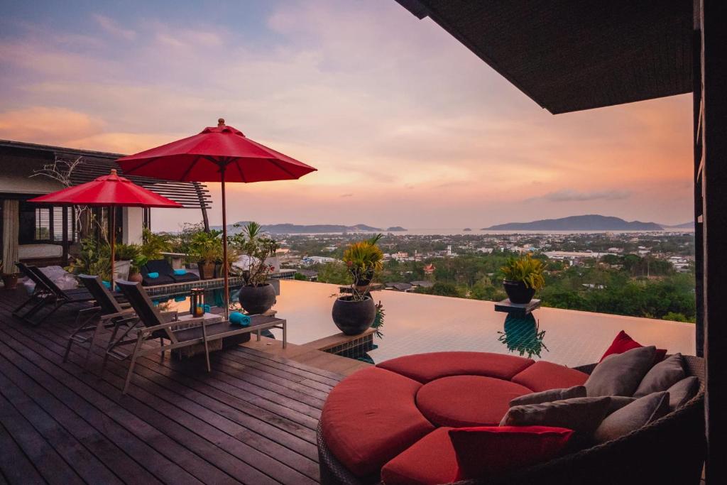 una terraza con mesa, sillas y sombrilla en Chalong Sunset Villa, en Chalong 