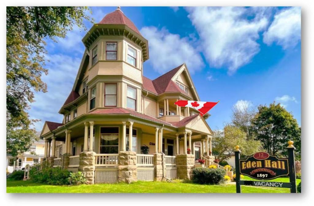 Una gran casa amarilla con una cruz roja. en The Eden Hall Inn, en Charlottetown