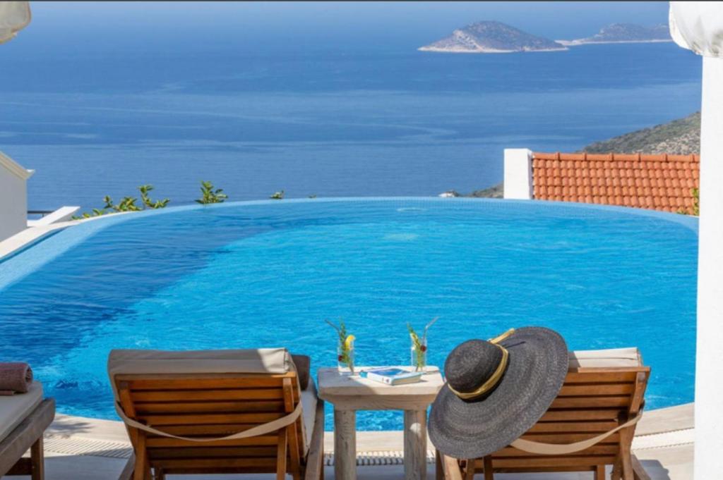 カシュにあるVilla Toros, 5 rooms,10 persons, Sea Views and Private Poolのテーブルの上に椅子2脚と帽子が置かれたプール