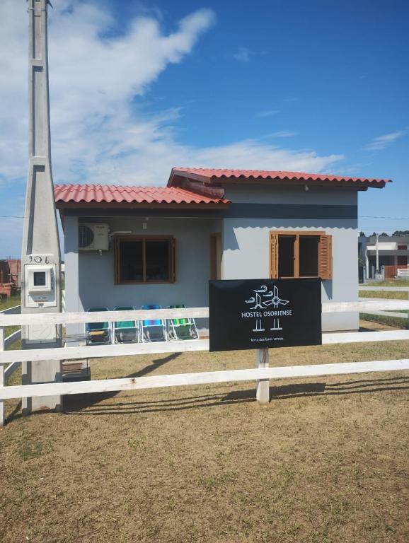 a small house with a sign in front of it at Hostel Osoriense in Osório