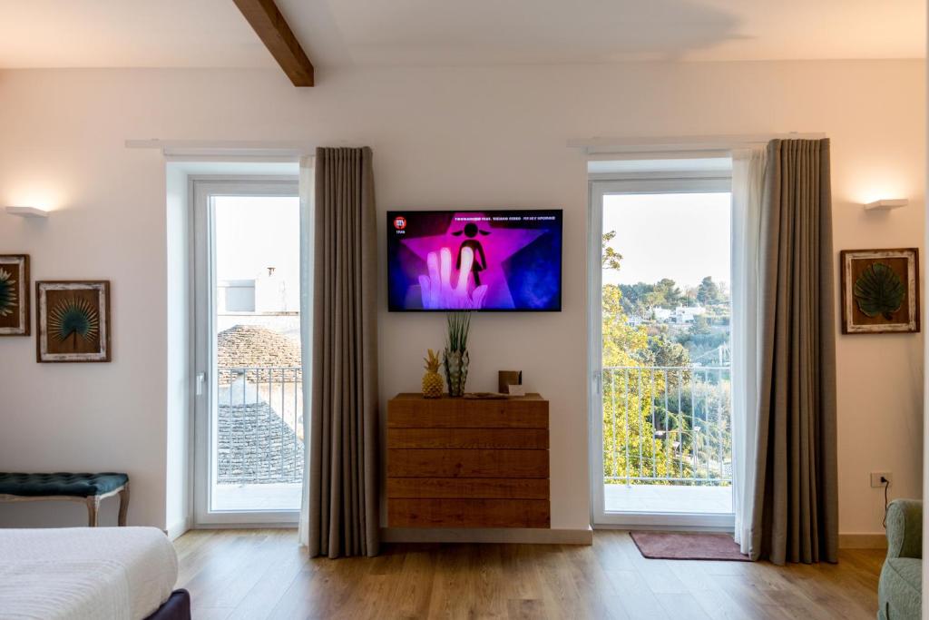 - une chambre avec une télévision murale et 2 fenêtres dans l'établissement Dimore Trulli Holiday, à Alberobello