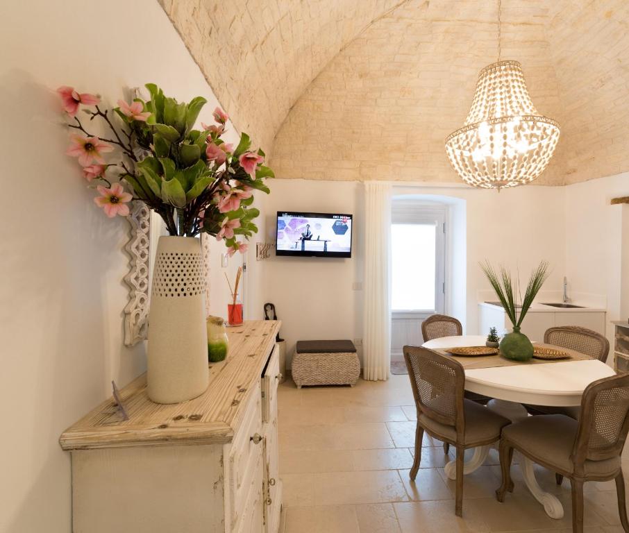 une salle à manger avec une table et un vase de fleurs dans l'établissement Dimore Trulli Holiday, à Alberobello