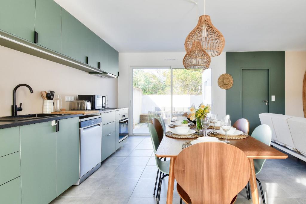 eine Küche und ein Esszimmer mit Tisch und Stühlen in der Unterkunft Belle maison pour 8 - 350m de la plage - Terrasse in La Guérinière