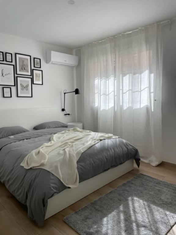 a white bedroom with a bed and a window at Little Rose apartment in Godella