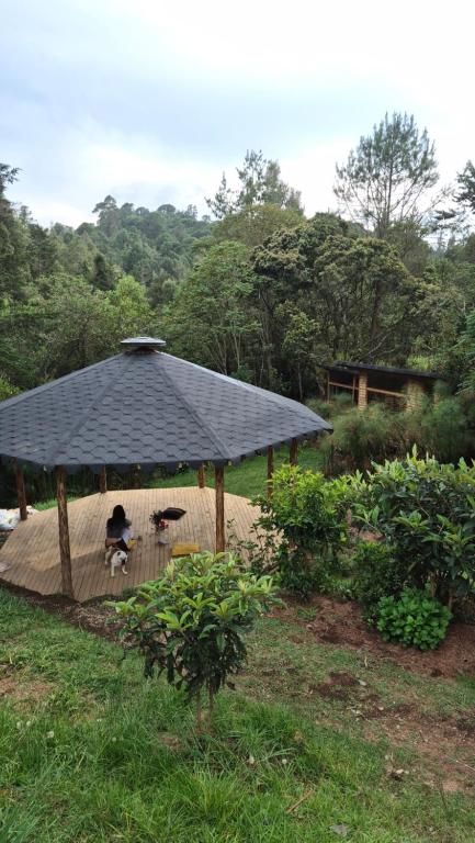 a black roofed gazebo with two people sitting under it at Cabaña Silencio en Casa Ilusión in Guarne