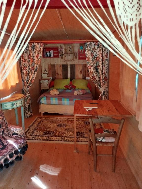 une petite pièce avec un lit et une table dans l'établissement Roulotte et Cabane Par Hasard, à Saint-Bressou