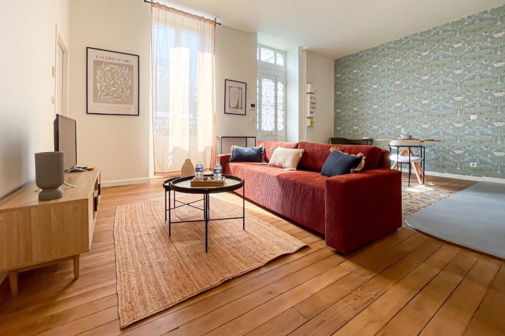 un salon avec un canapé rouge et une table dans l'établissement OIQIA • Berry, à Bourges