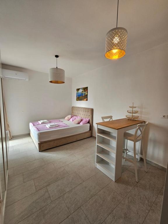 a bedroom with a bed and a table and a desk at Calypso Sea View Apartament Saranda in Sarandë