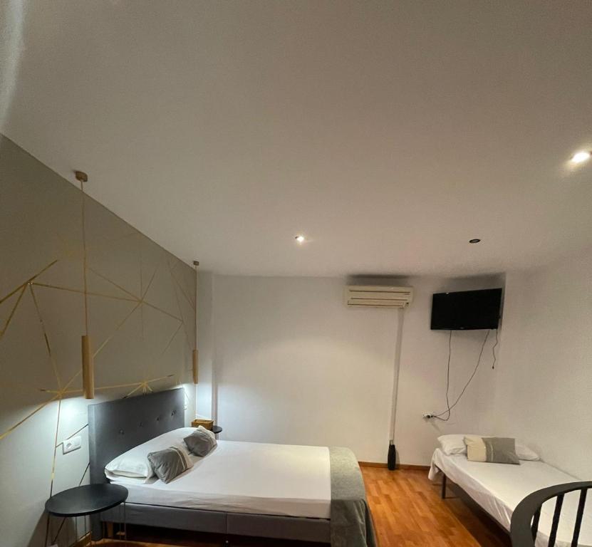 a bedroom with two beds and a tv on the wall at Apartamentos de la Luz in Granada