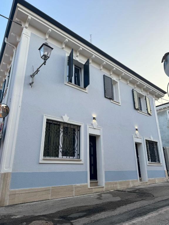 a white house with blue windows and a street at Casa Magenta Apartment 5 in Valeggio sul Mincio