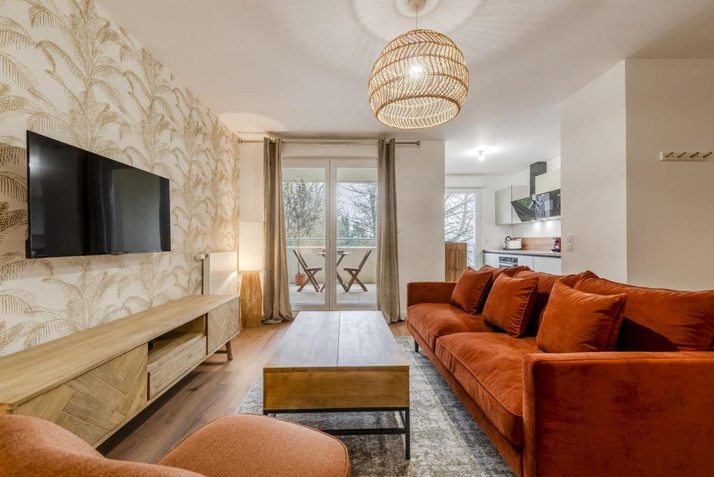 un salon avec un canapé et une télévision à écran plat dans l'établissement OIQIA • Palmeraie, à Bussy-Saint-Georges