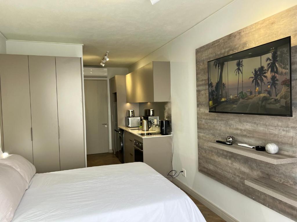 a bedroom with a white bed and a kitchen at One Rosebank in Johannesburg
