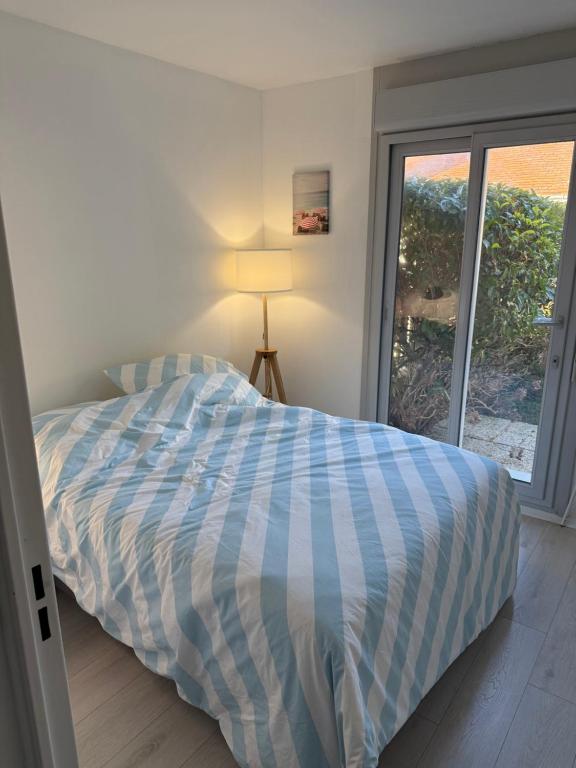 ein Bett mit einer blauen und weißen Bettdecke in einem Schlafzimmer in der Unterkunft Cabourg, T2 jardin proche plage in Cabourg