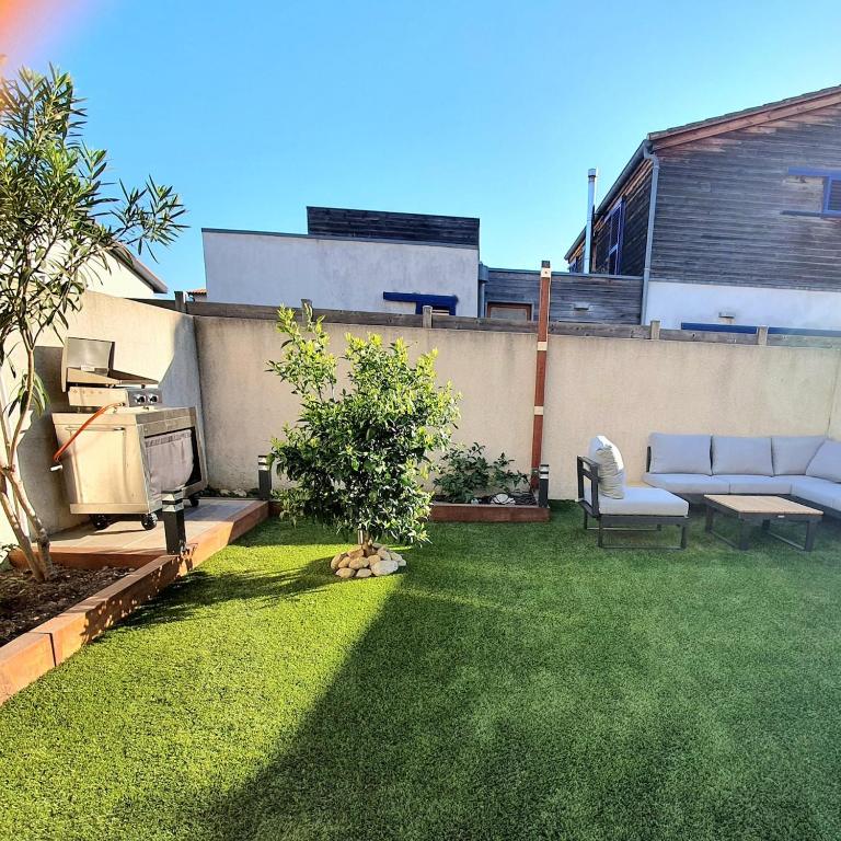 un jardin avec un canapé et une chaise sur l'herbe dans l'établissement L'Argelésienne, à Argelès-sur-Mer