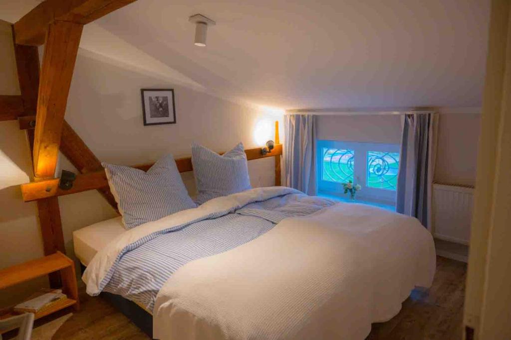 una camera da letto con un grande letto bianco con una finestra di Ferienwohnung Himmelsbesen - Inselhof Fehmarn a Fehmarn