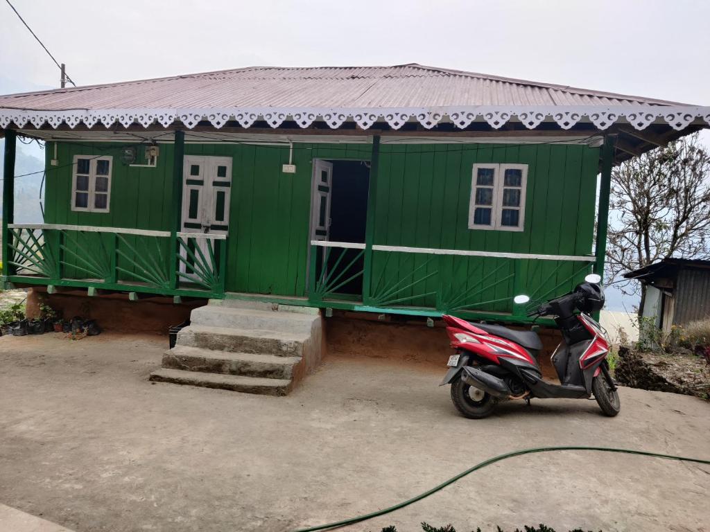 a scooter parked in front of a green house at Kousani Naranga Farmstay-Kagey in Pedong