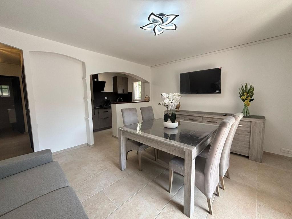 Sainte-Maxime appartement 45m avec jardin de 35m في سانت ماكسيم: غرفة طعام مع طاولة وكراسي وتلفزيون