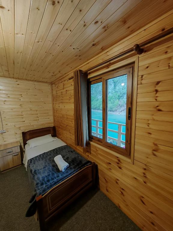 a bedroom with a bed and a window in a cabin at Riverside Komani Lake in Koman