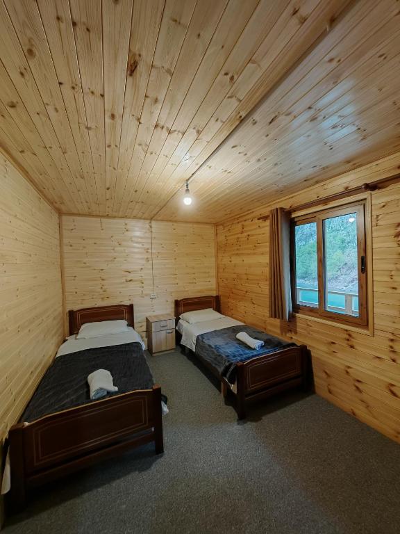 a bedroom with two beds in a log cabin at Riverside Komani Lake in Koman