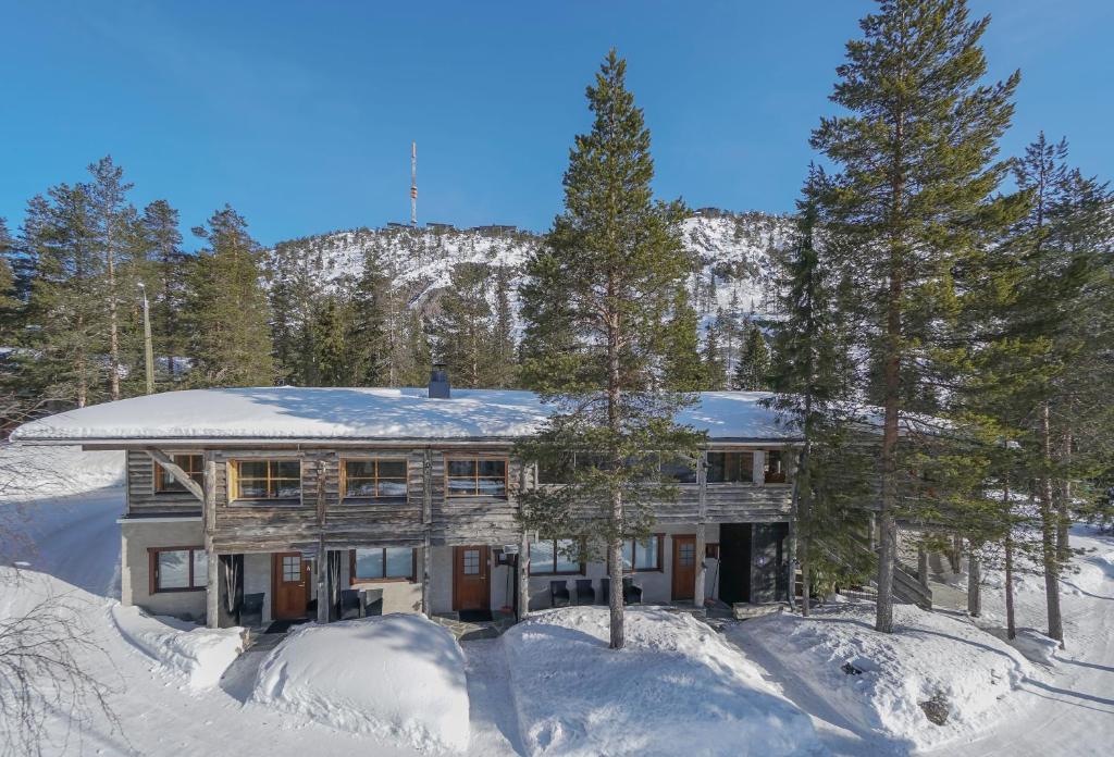 a house is covered in snow with trees at Vanhan Karhun Huoneistot in Ruka