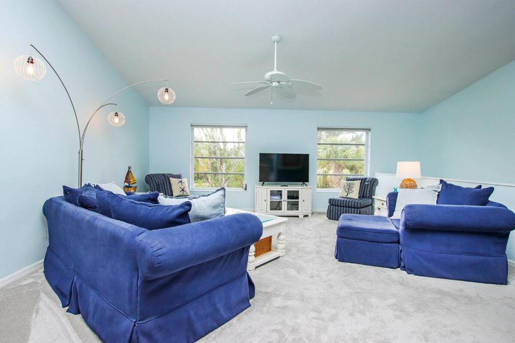 YbelにあるCharming Sanibel Island Home Minutes From The Beachの青いソファ2脚とテレビのあるリビングルーム