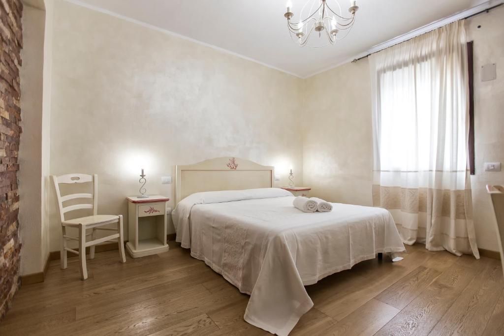 um quarto com uma cama branca, 2 mesas e um lustre em Morpheo Rooms em Alghero