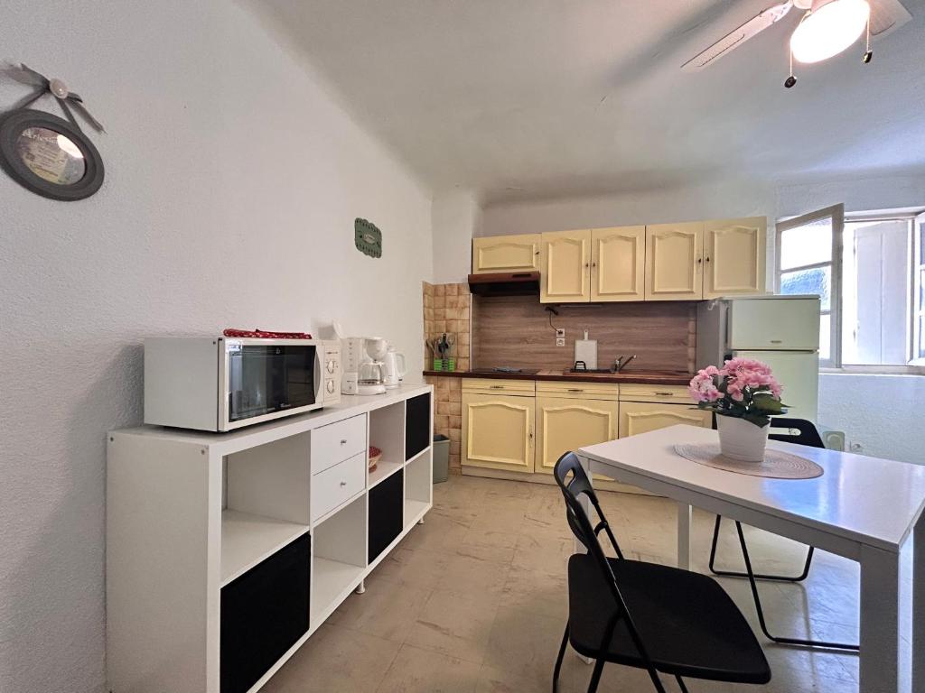 une petite cuisine avec une table et un micro-ondes dans l'établissement Studio Tournesol au pied des Arènes, à Arles